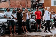 Young men pose with cars and motorcycles in an urban setting, capturing street culture.