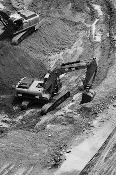 Black and white image of excavators working at a construction site in Ciudad de México, showcasing industrial activity.