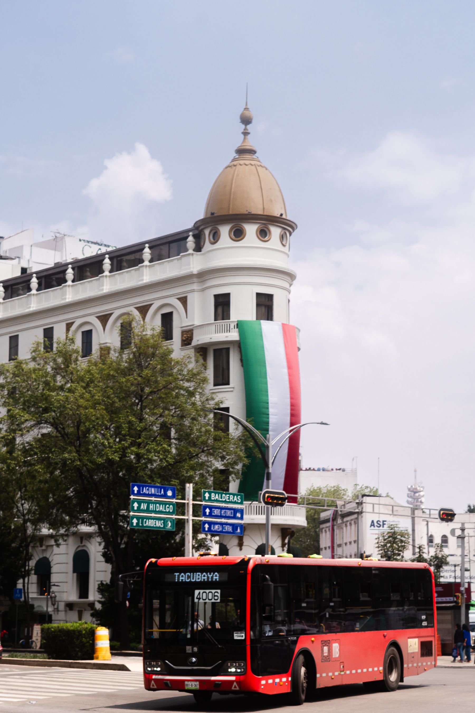 A vibrant city scene in Mexico City featuring historic architecture and public transport.