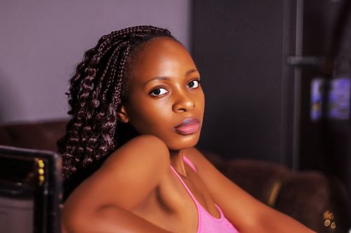 Free Elegant portrait of a woman with braided hair wearing a pink top indoors. Stock Photo