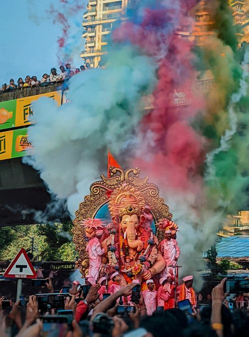 Free Ganesha idol procession in Mumbai with colorful smoke and crowds during Ganesh Chaturthi festival. Stock Photo