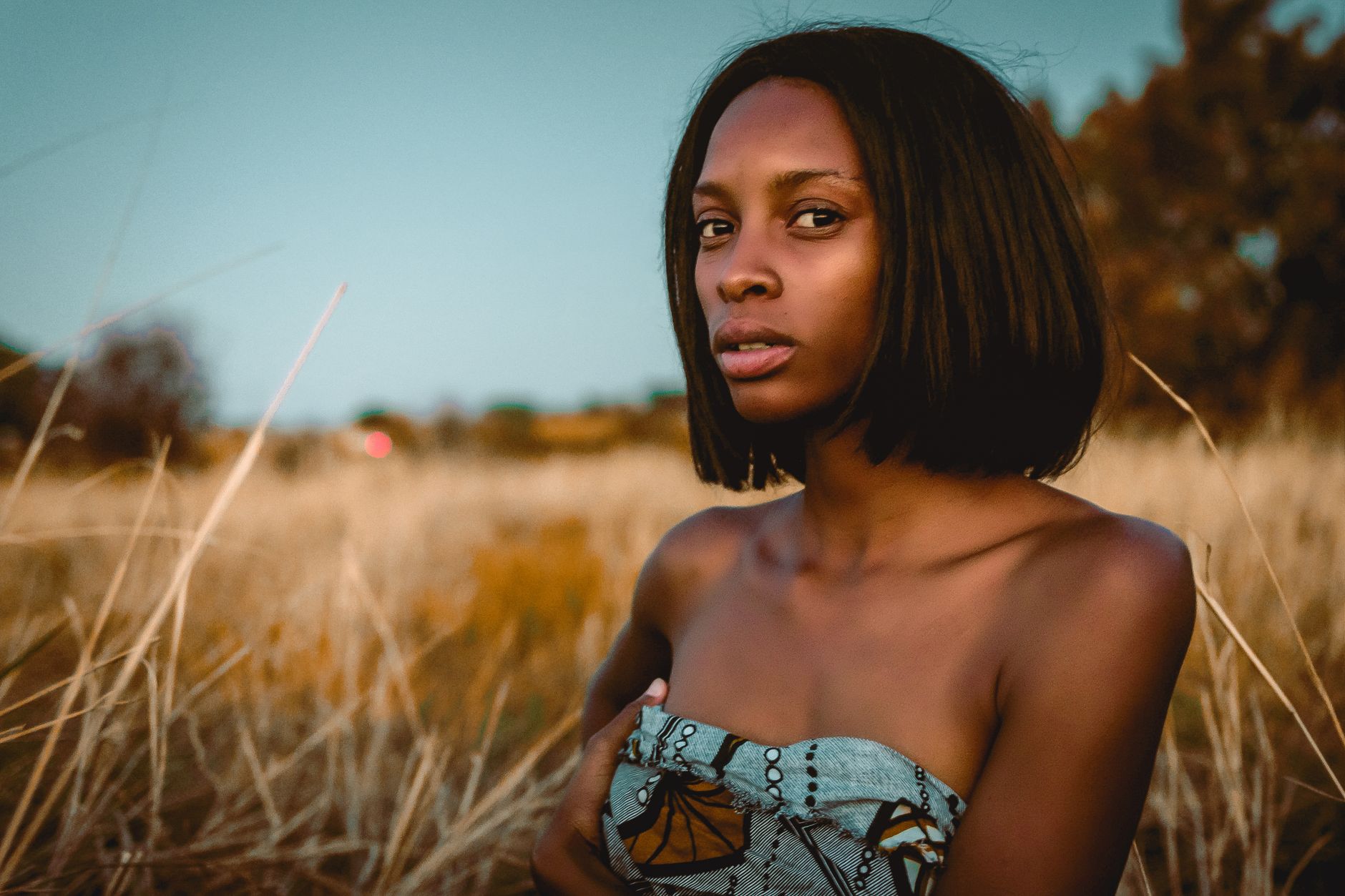 Portrait of a woman against a rural South African sunset backdrop.