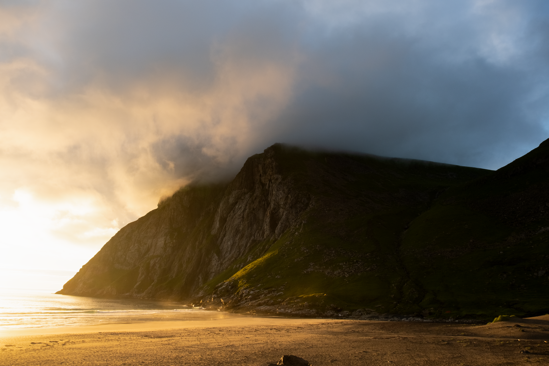 Ethereal mist over a coastal mountain at sunrise with soft light creating a serene atmosphere.