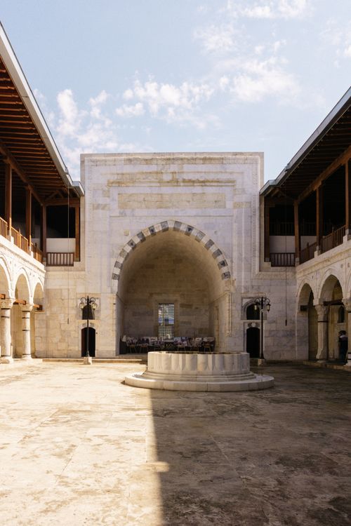 Free Stunning historic courtyard featuring a stone arch and symmetrical columns under a blue sky. Stock Photo
