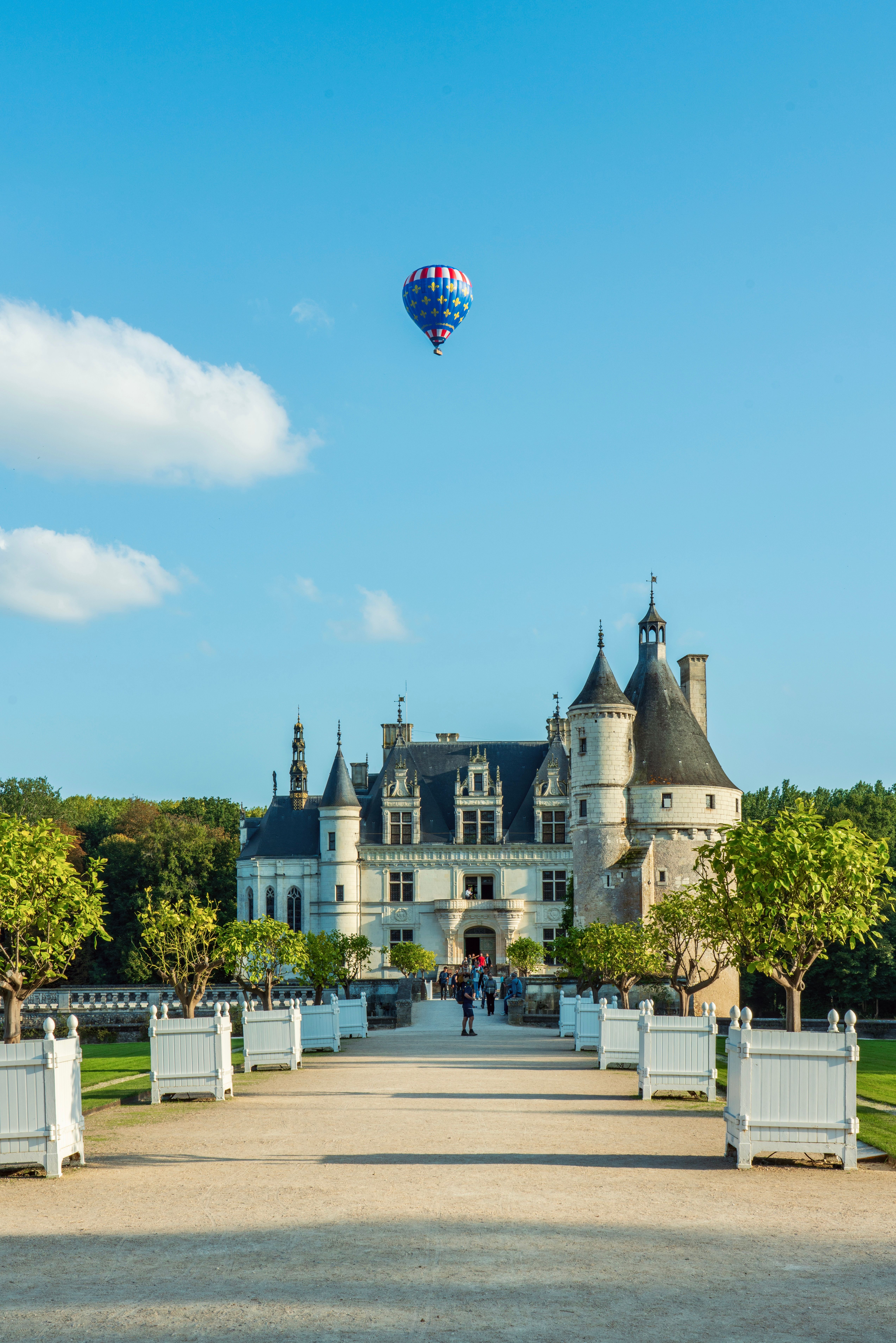 Free The Chateau de Chenonceau with a colorful hot air balloon floating above on a sunny day. Stock Photo