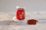 A glass of Turkish tea and a biscuit on a sunlit table, perfect for a serene afternoon break.