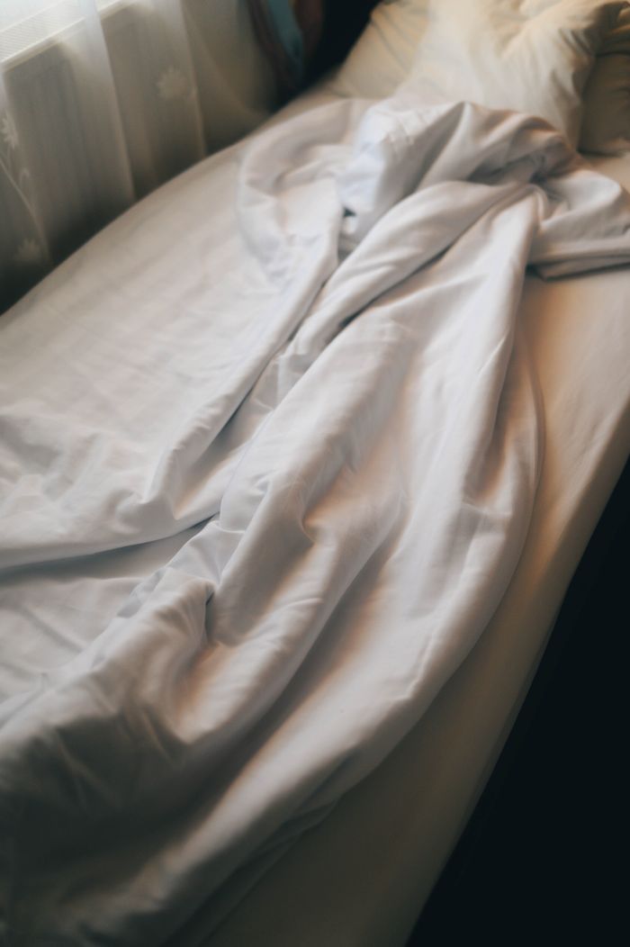 Creased white bed linen in warm morning light, by Diana on Pexels
