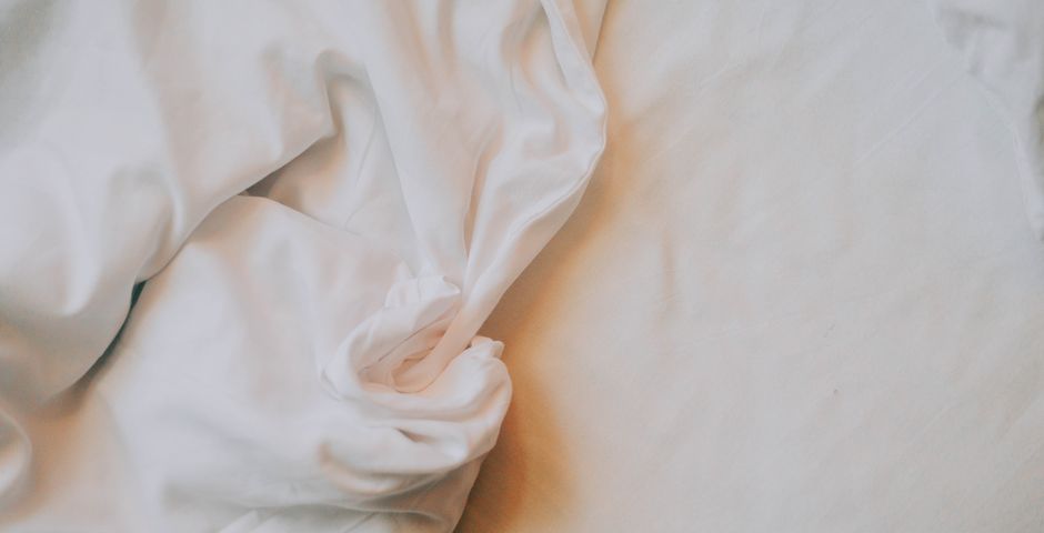 Close-up of crumpled white bed sheets — check the sheets and seams for dark spots and blood smears