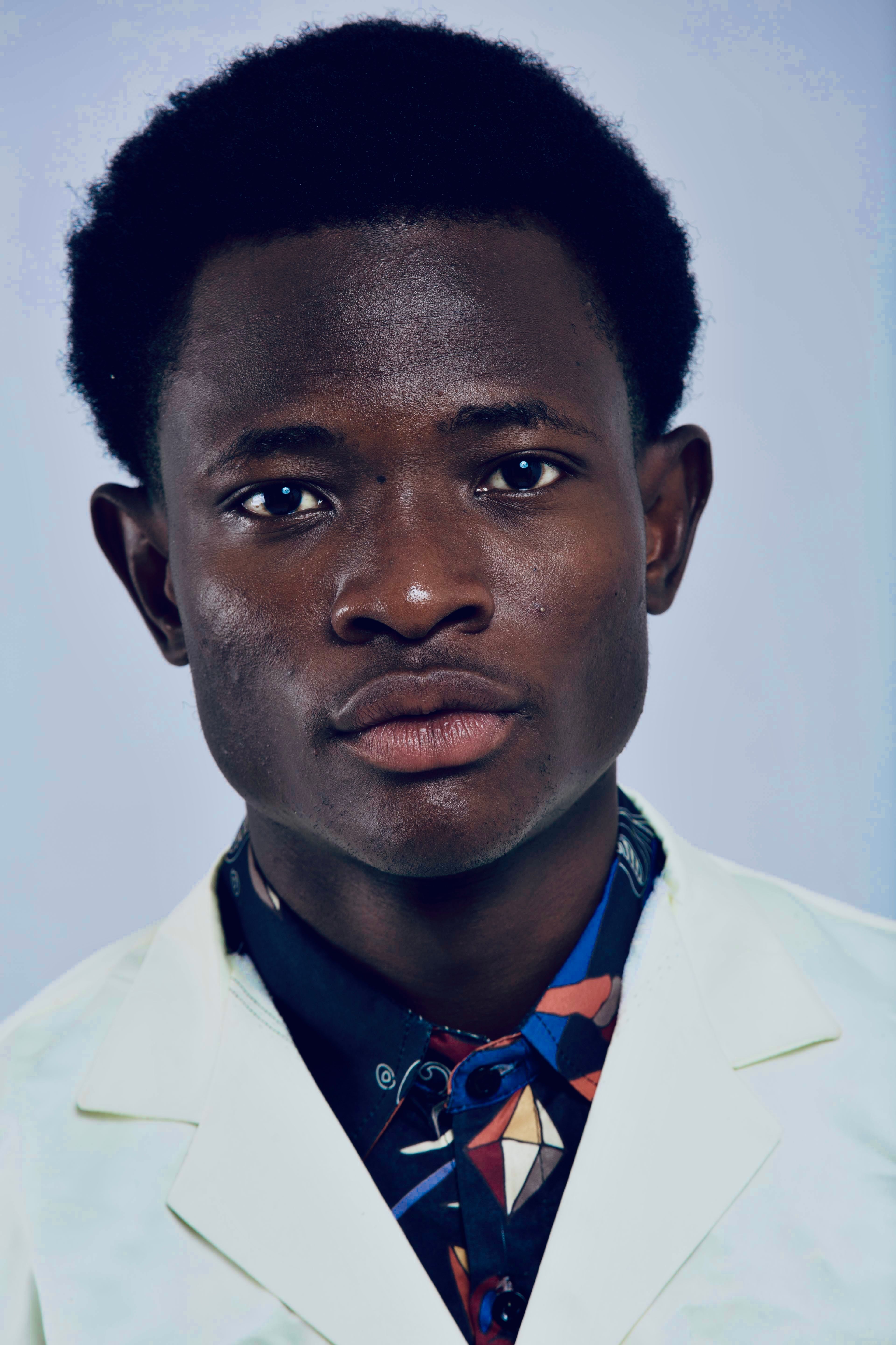 Striking portrait of an adult man wearing a white lab coat and patterned shirt, exuding confidence.