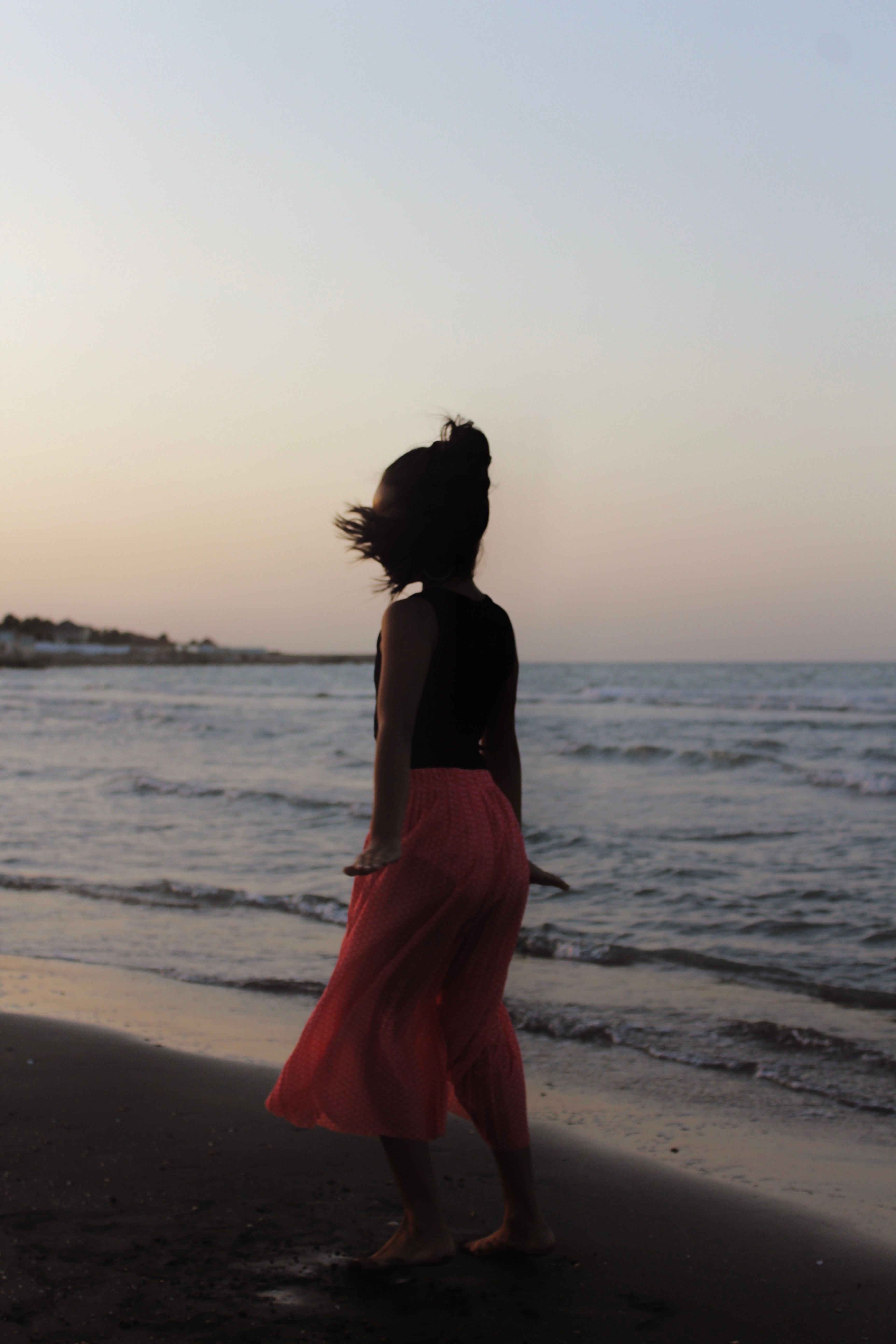 Silhouette of Woman Walking on a Beach at Sunset · Free Stock Photo
