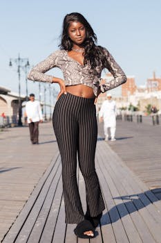 一位自信的女子身着休闲别致的服装，在阳光明媚的木板路上摆着姿势