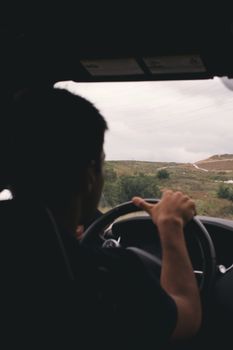 Person driving through countryside under an overcast sky, capturing an adventurous mood.
