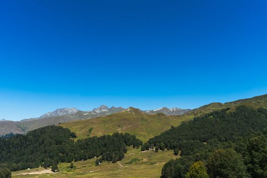 A serene mountain landscape with green hills and a bright blue sky, perfect for nature enthusiasts.