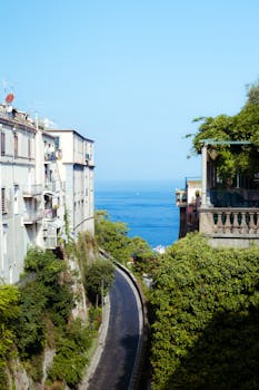 Charming street in Sorrento, Italy with lush greenery and a stunning view of the blue ocean.