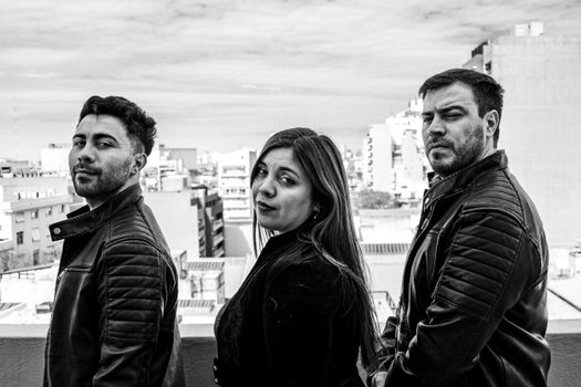 Black and white portrait of three adults in Buenos Aires, Argentina, with cityscape.
