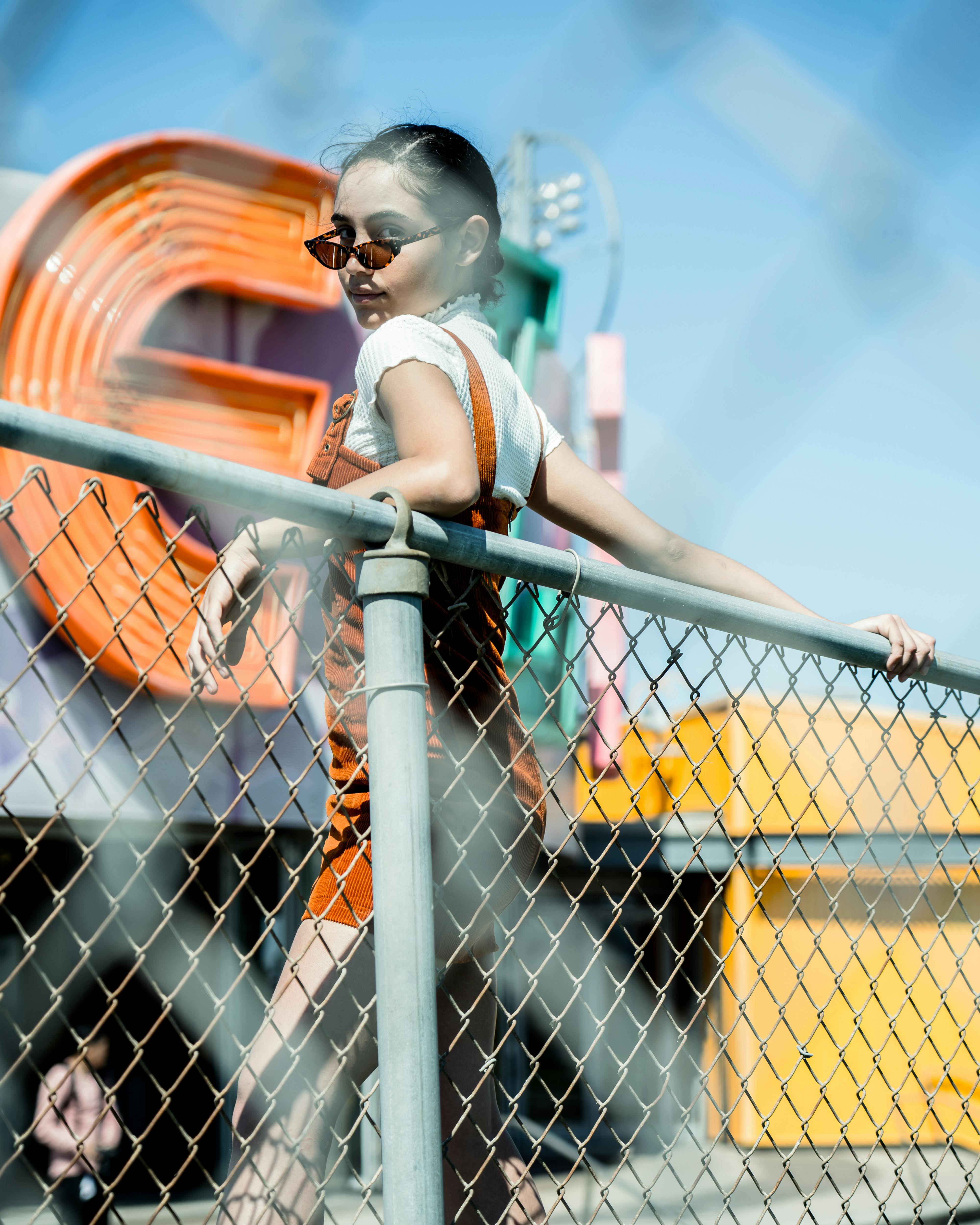 阳光明媚的日子里，一位戴着太阳镜的时尚年轻女子在充满活力的霓虹灯旁摆姿势