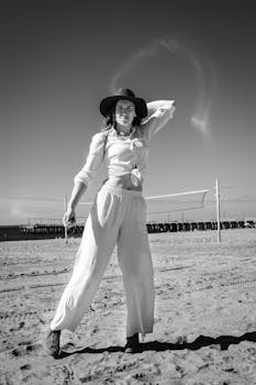 一位优雅的女人身着休闲装，在阳光明媚的海滩上摆着姿势，天空晴朗