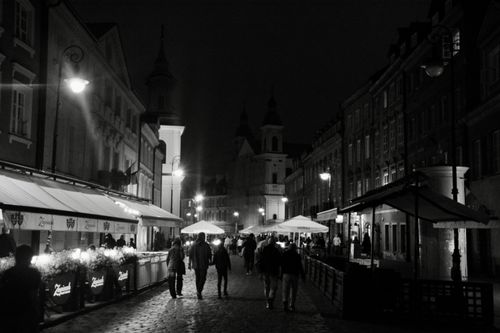 Free Black and white photo of a bustling street in Warsaw's Old Town at night. Stock Photo