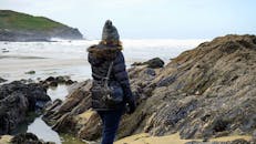 一位穿着冬装的女人在海边的岩石海岸探索