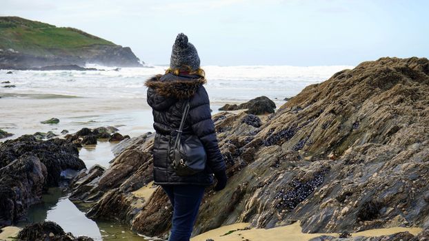 一位穿着冬装的女人在海边的岩石海岸探索