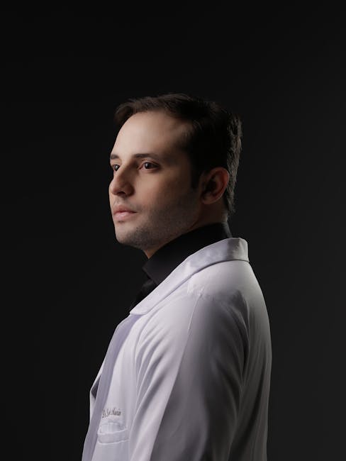 Side profile of a male doctor in a white coat against dark backdrop.