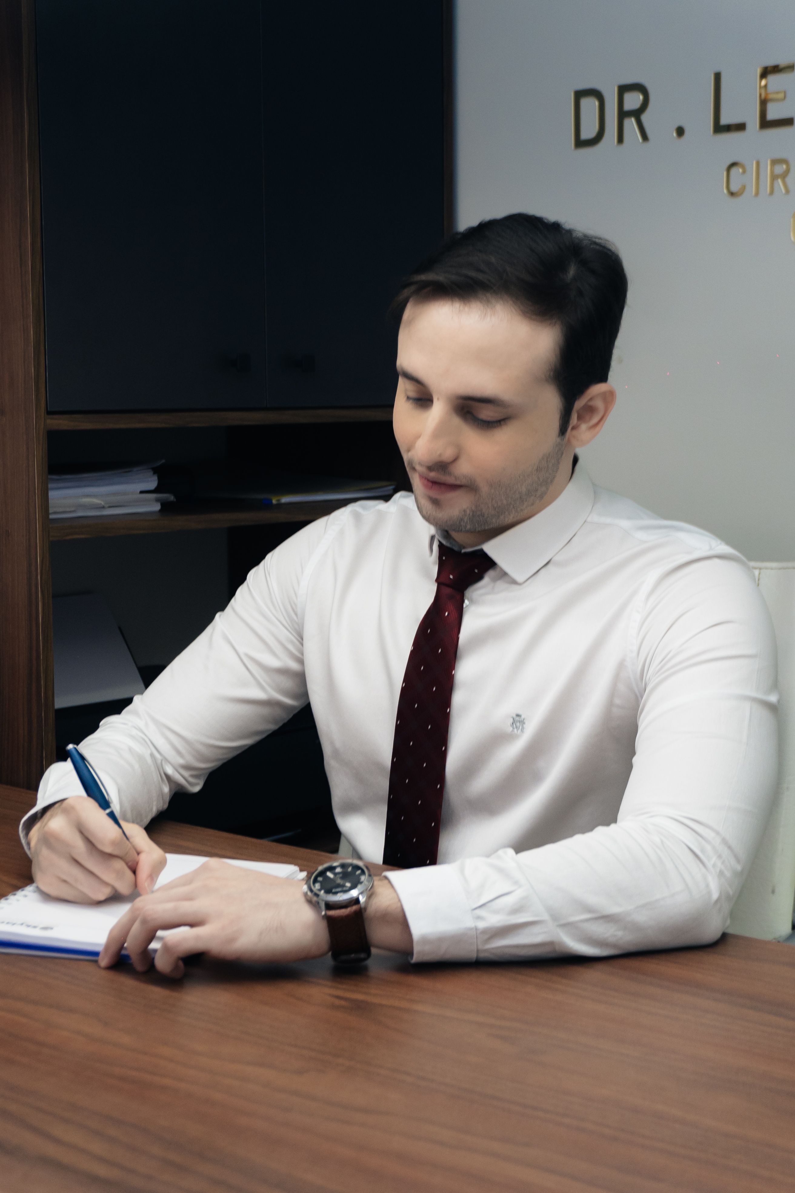 A professional man in an office taking notes in a notebook.
