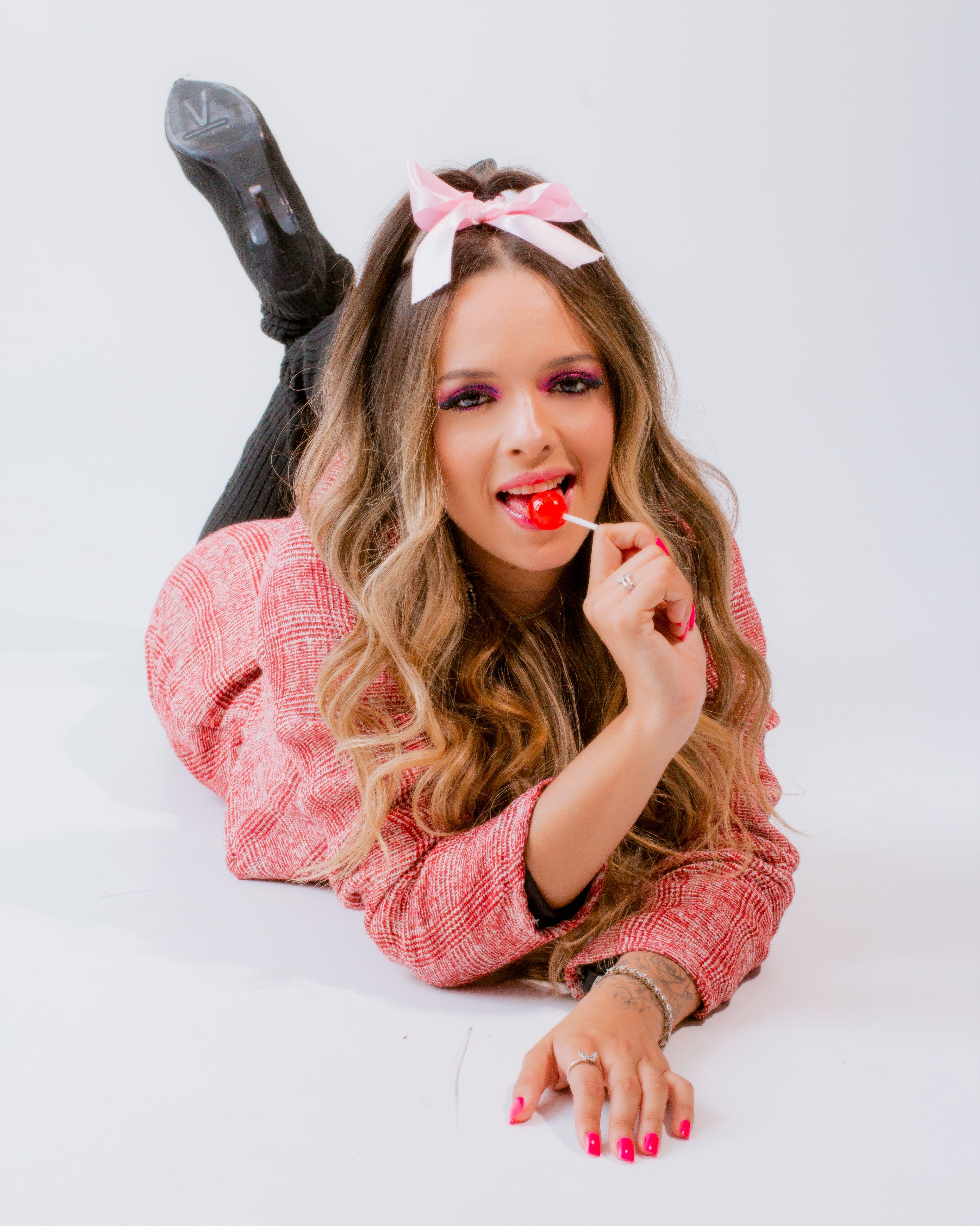 Playful adult woman with long hair and lollipop in casual pose.