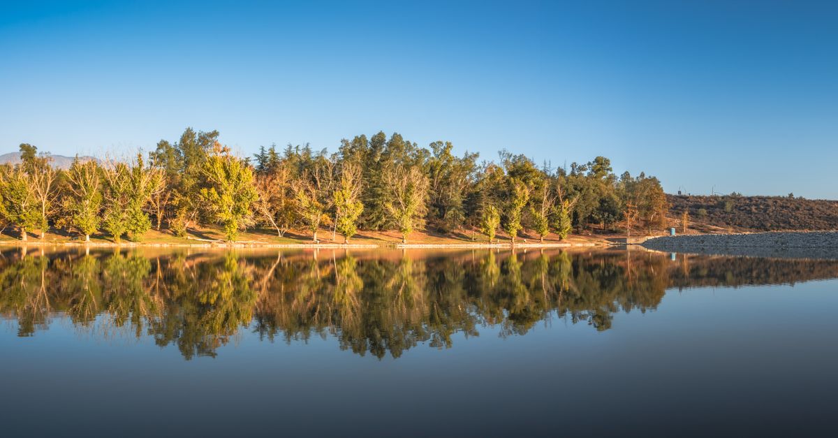 Beautiful fall foliage and clear blue sky reflected in a tranquil lake in Yucaipa, California.