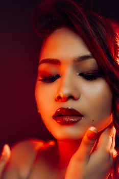 Stunning close-up portrait with warm red lighting highlighting a woman's face.