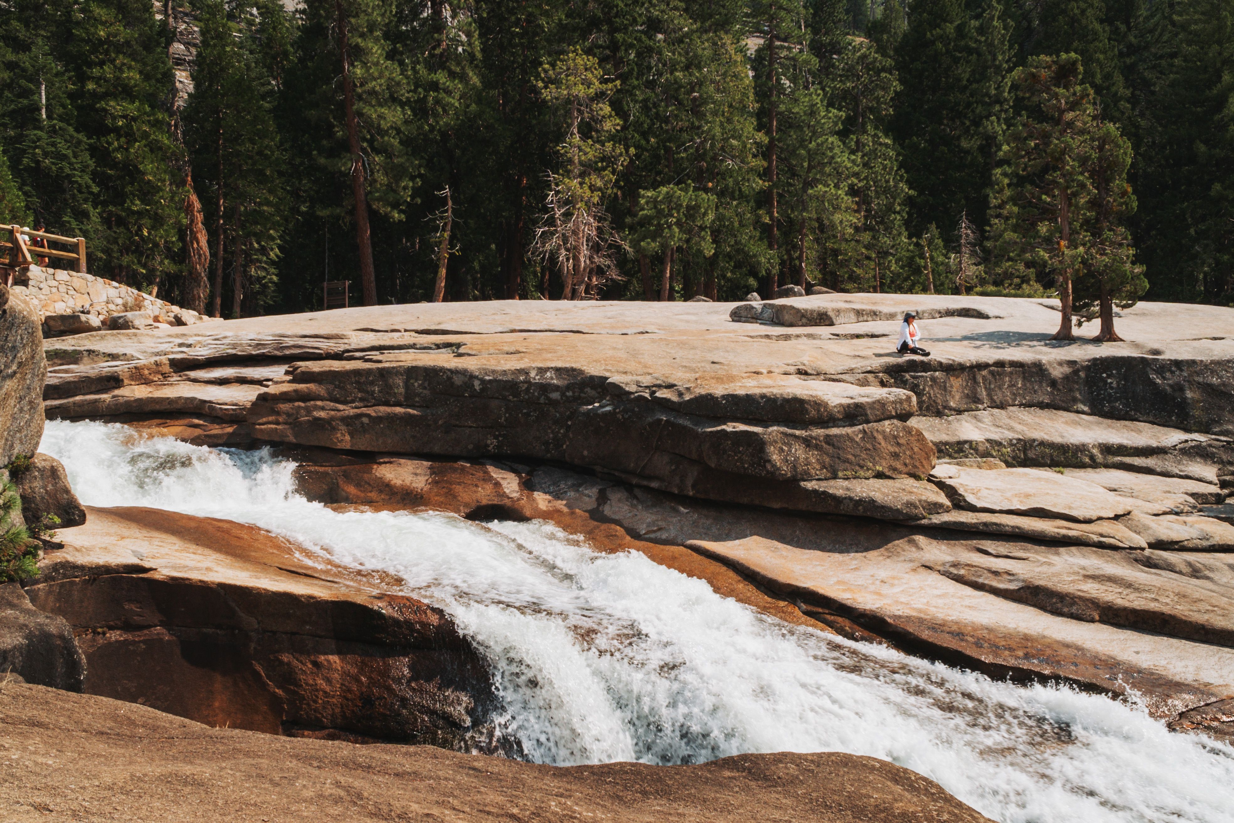 A serene moment of meditation by a waterfall in Yosemite Valley with lush forest surroundings.