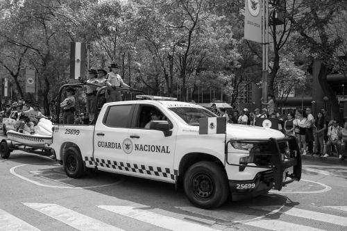 Free Black and white photo of Mexican National Guard vehicle during a parade with officers standing at the back. Stock Photo