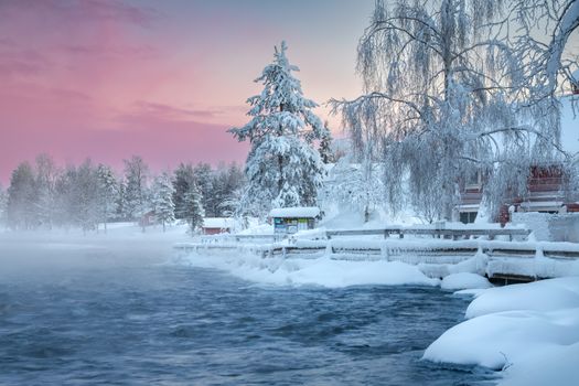 Serene winter landscape with snowy trees and a frozen river at sunset.
