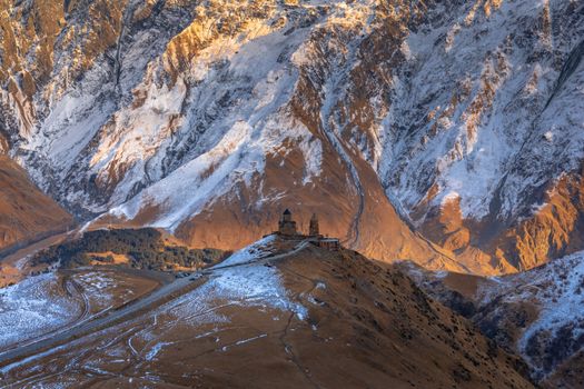 Stunning view of Gergeti Trinity Church surrounded by majestic snowy peaks and rugged terrain.