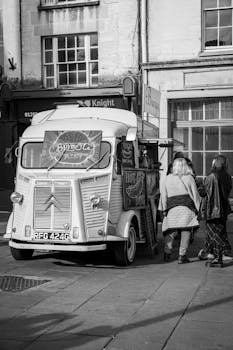 Black and white photo of a vintage food truck on a busy street in London, England.