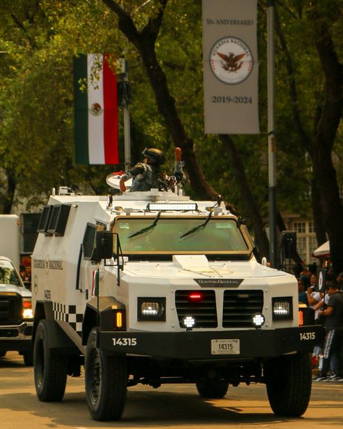 Free Armored vehicle participating in city parade, celebrating national forces anniversary with spectators and flags. Stock Photo
