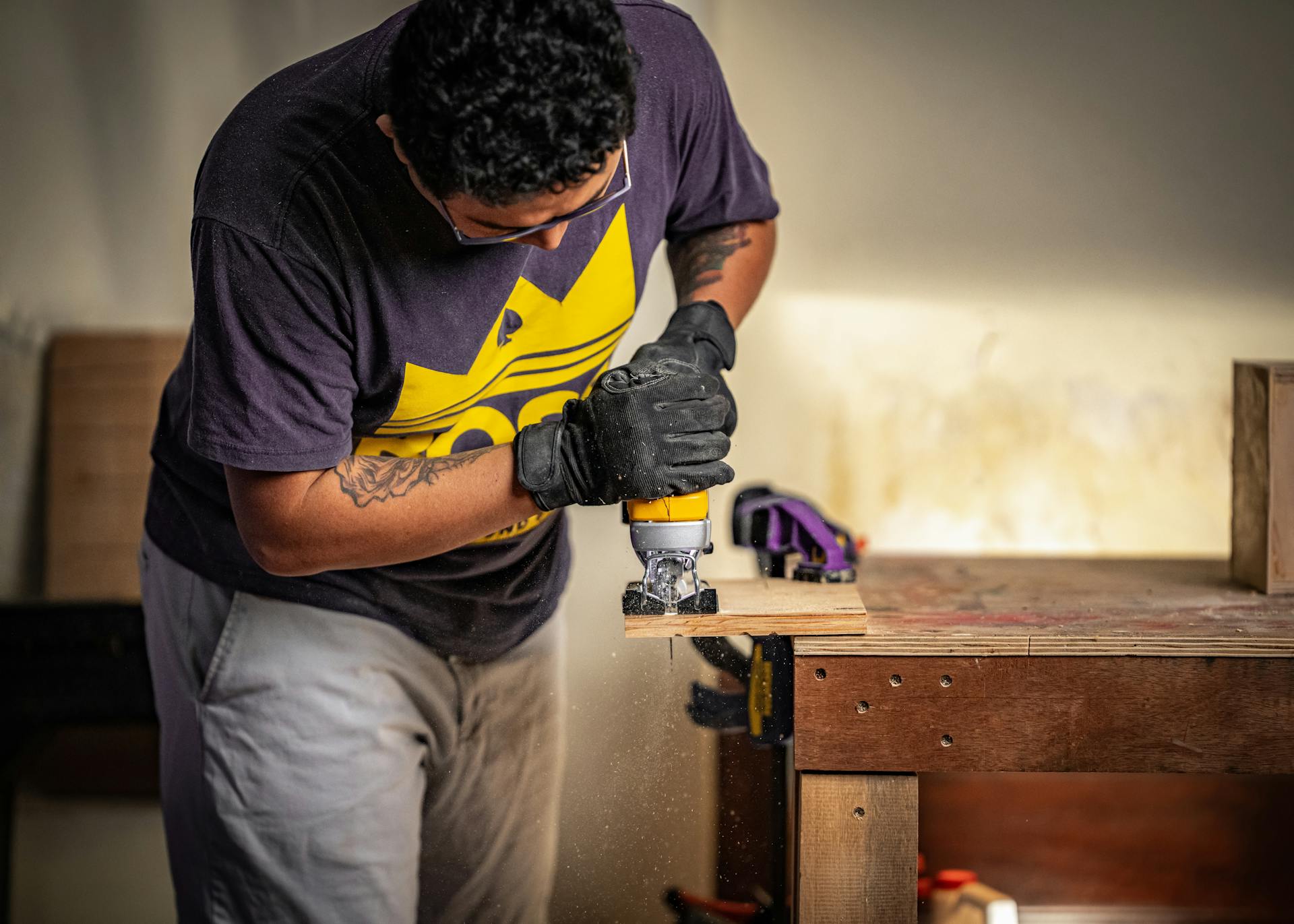 A carpenter in Costa Rica skillfully uses a power tool in a workshop environment.