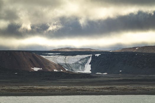 Dramatic Arctic landscape showcasing erosion and glaciers under a cloud-covered sky.