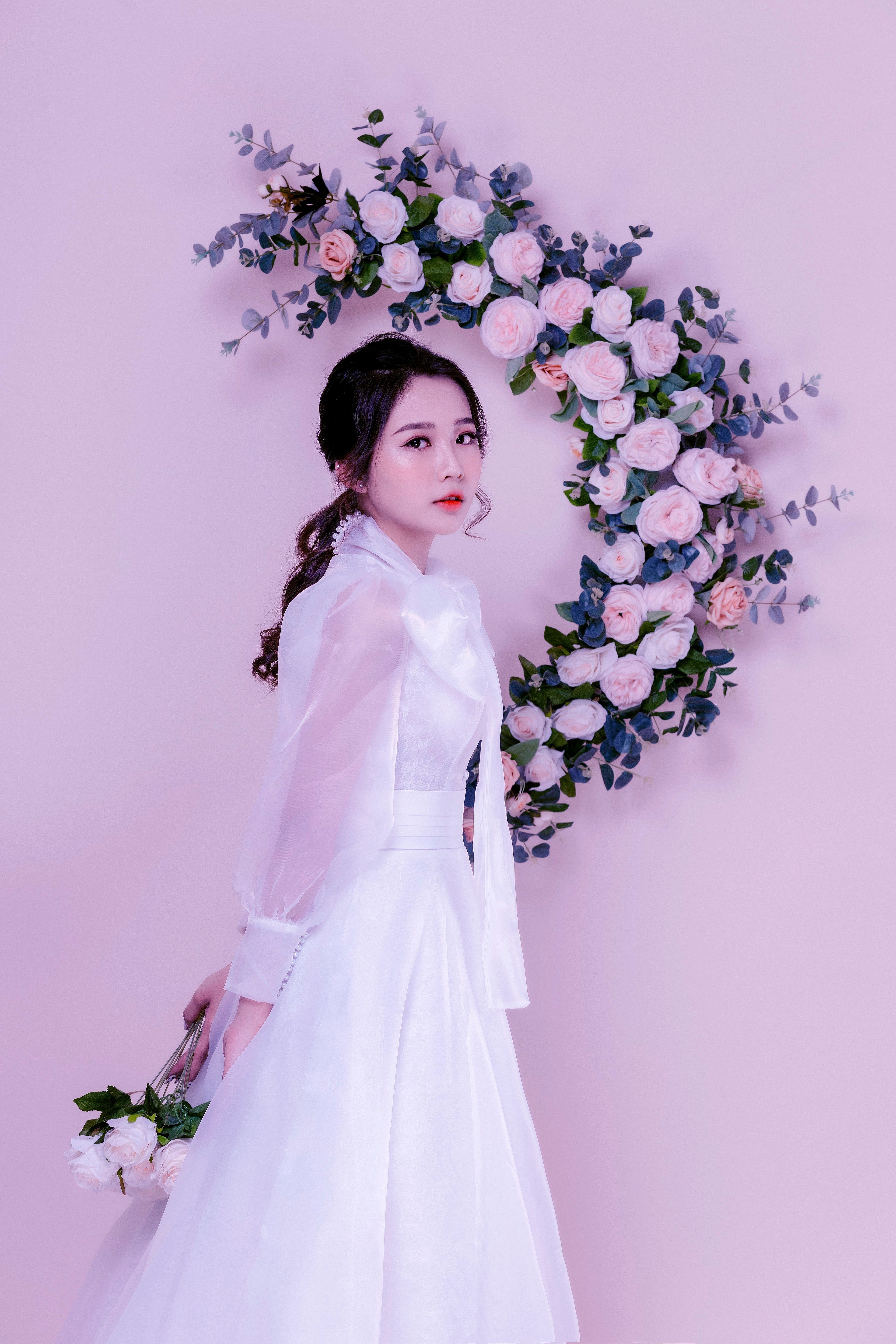 Beautiful bride in white with floral wreath background. Elegant and serene portrait.