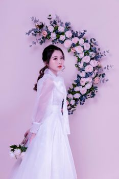 Beautiful bride in white with floral wreath background. Elegant and serene portrait.