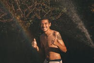 阳光下，微笑的年轻人竖起大拇指，户外有彩虹效应