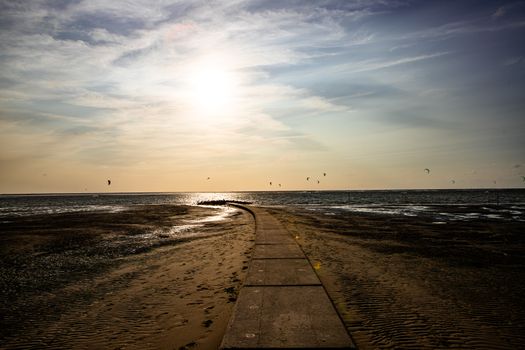 Peaceful sunset over a serene beach pathway on Borkum island, capturing beautiful seascape views.