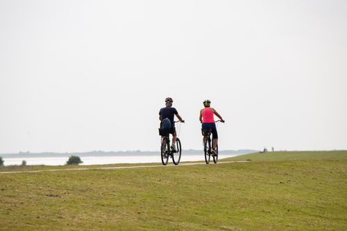 Free Two cyclists enjoying a scenic ride along the coast of Borkum, Germany on a clear summer day. Stock Photo
