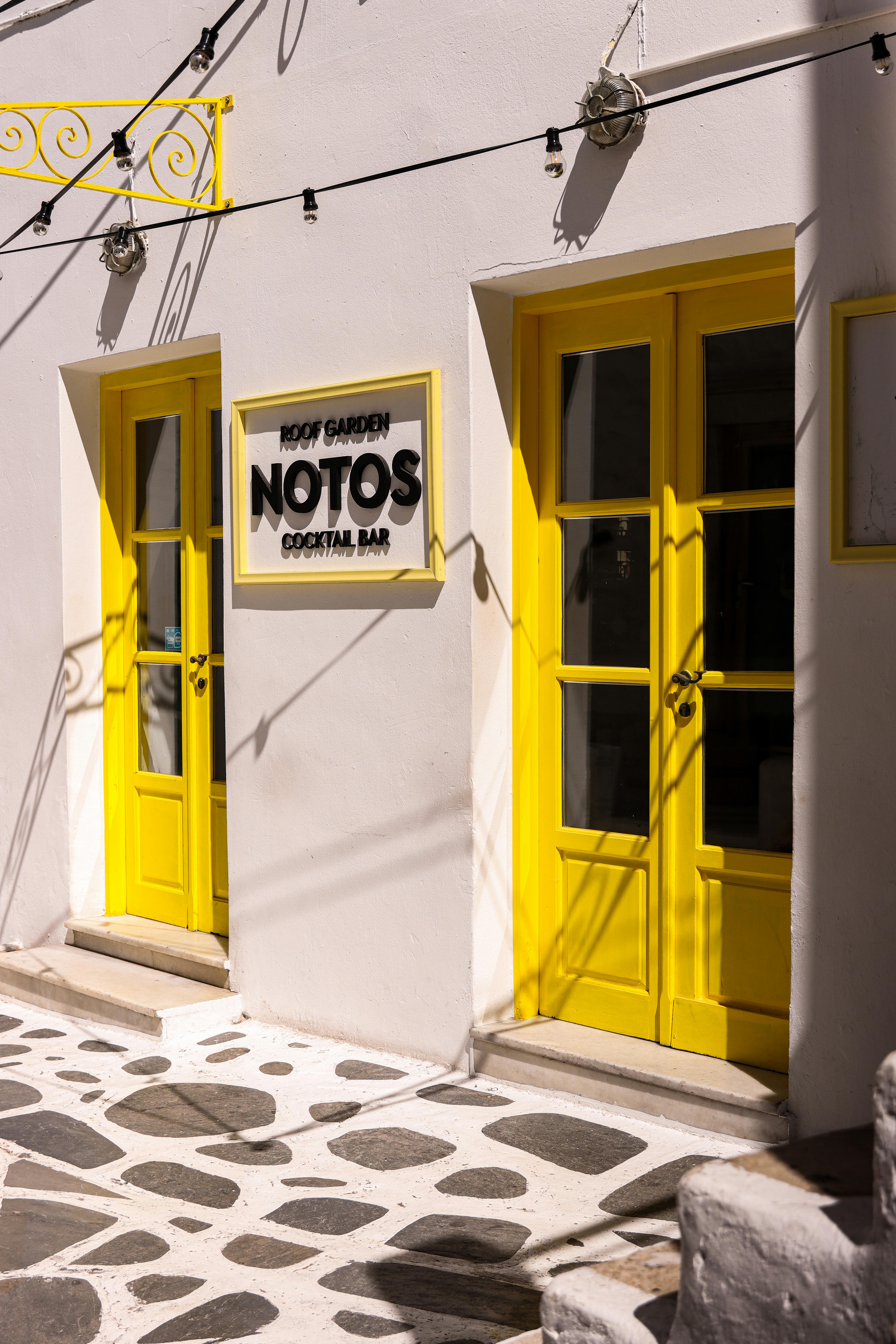 charming yellow doors of notos cocktail bar in naxos