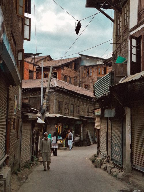 Free Charming old city alley with traditional buildings and locals in daily activities. Stock Photo