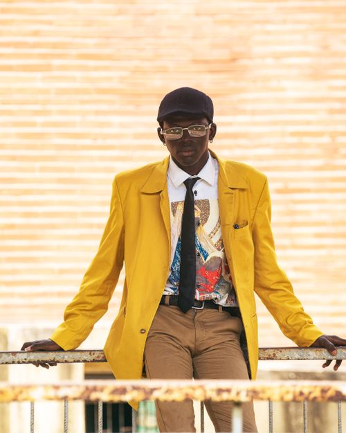 Free Fashion-forward man wearing yellow coat and colorful shirt in an urban setting. Stock Photo