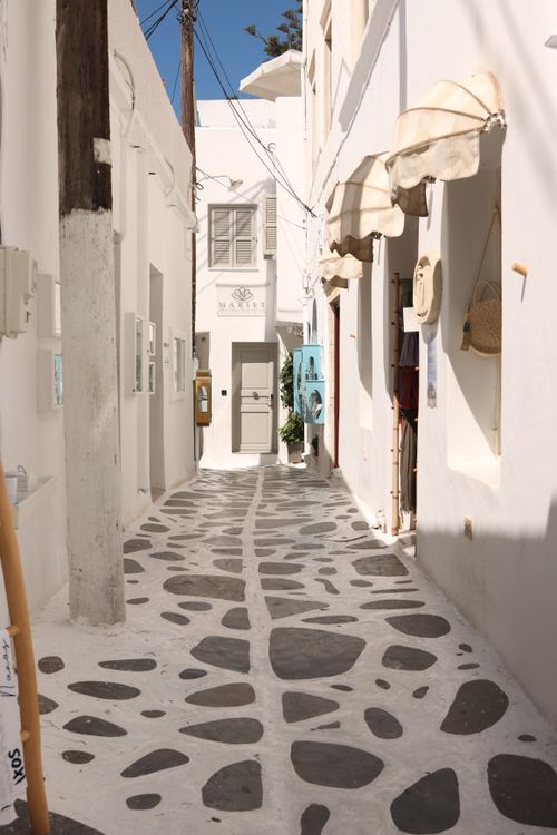 Free Scenic view of a traditional cobbled street in Naxos, Greece, showcasing Cycladic architecture. Stock Photo