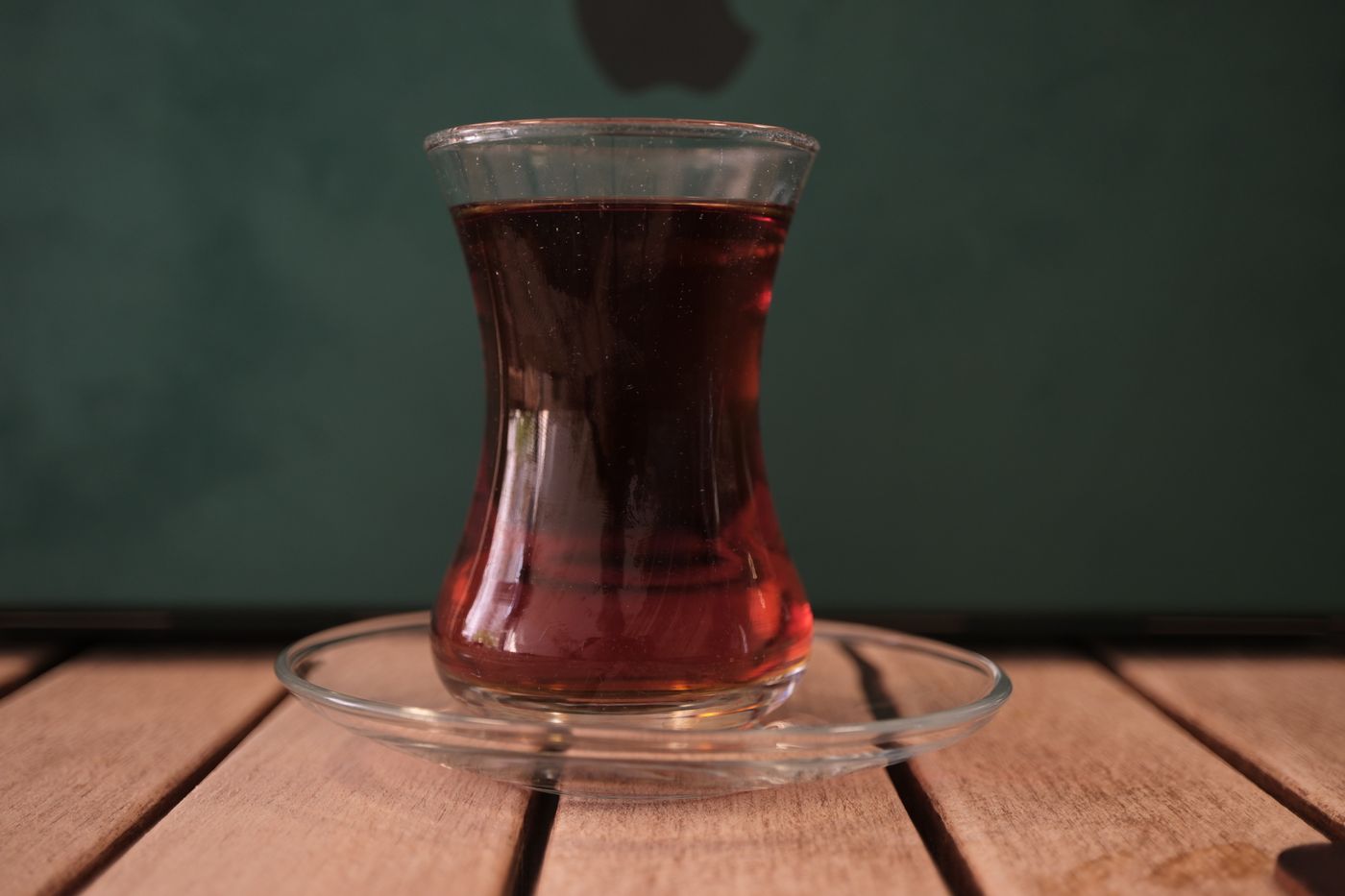 A tulip-shaped glass of traditional Turkish tea served on a wooden table
