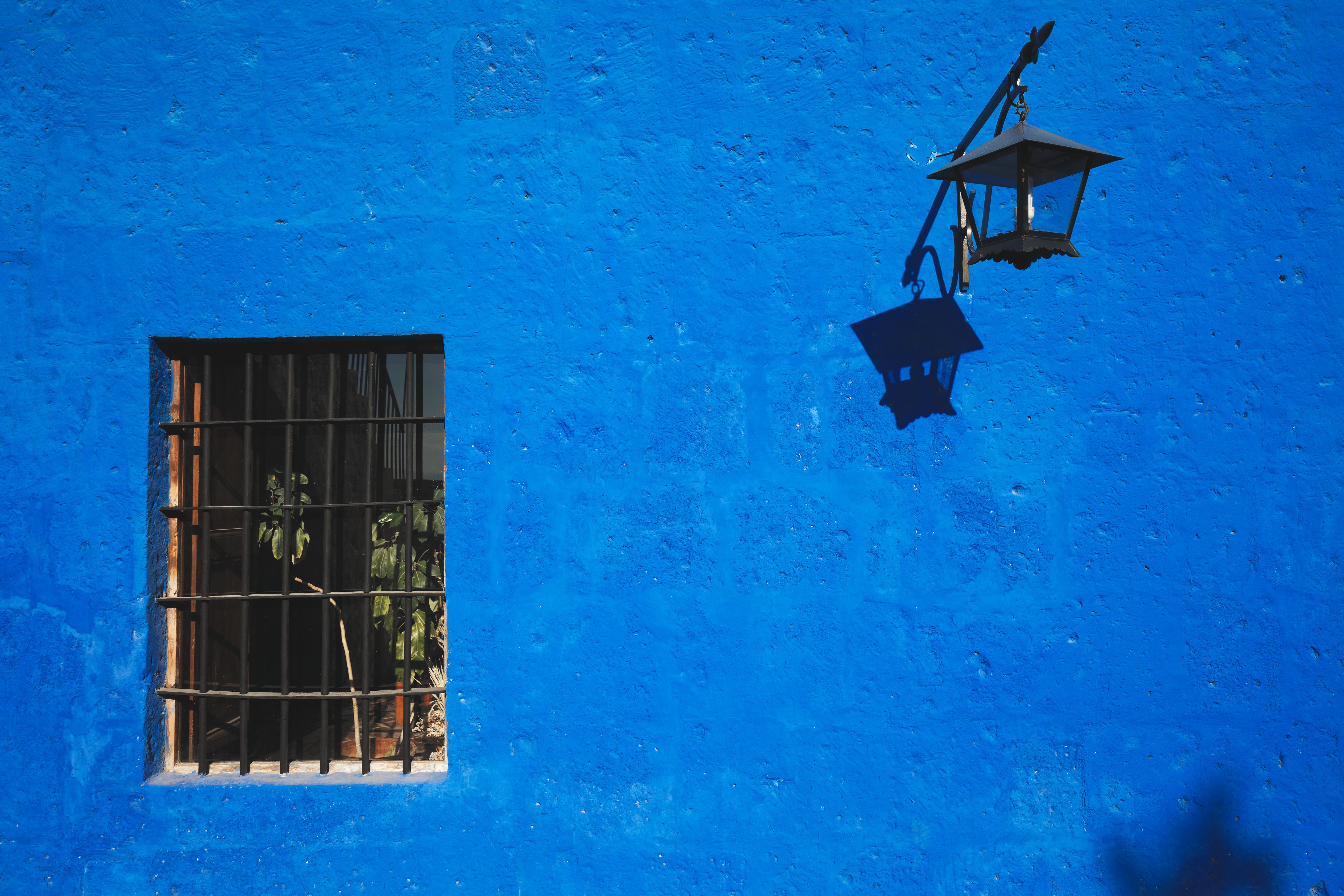 Fotomural Pared azul brillante con ventana y sombra de farol en Arequipa, Perú.
