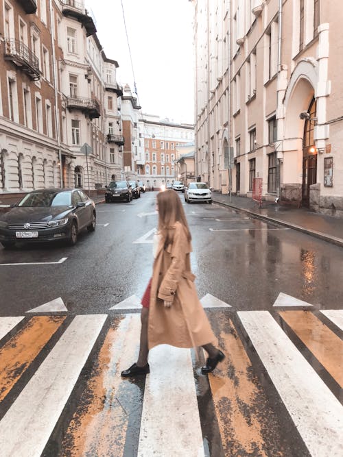 穿棕色大衣過馬路的女人的照片