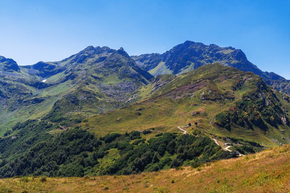 Breathtaking view of lush green mountains in Гагра under a clear blue sky.
